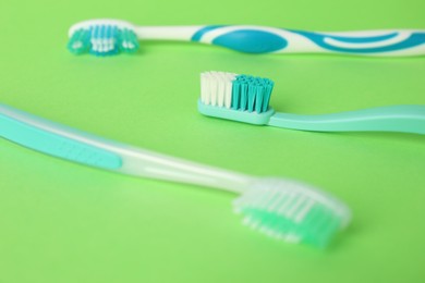 Photo of Different plastic toothbrushes on green background, closeup