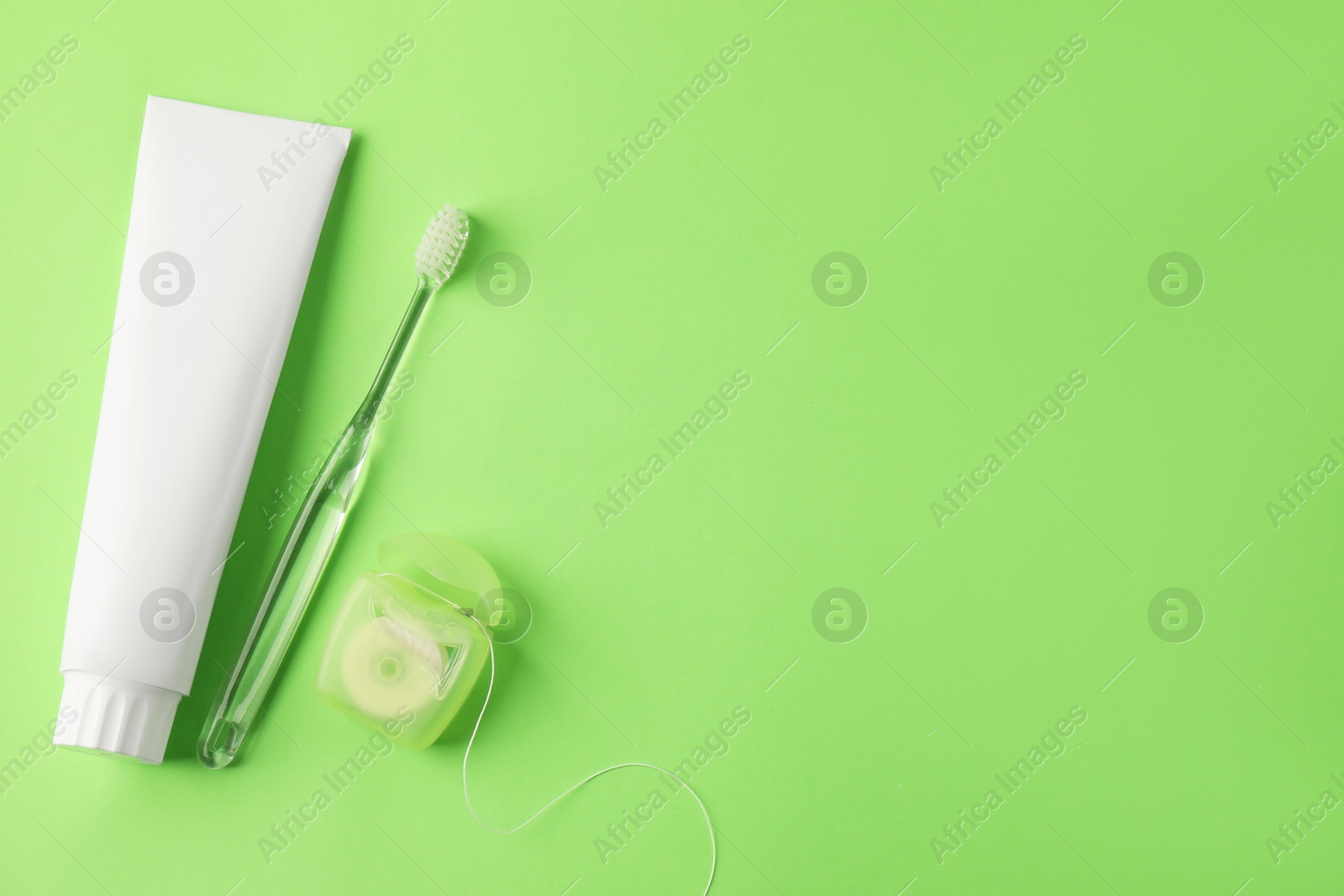 Toothbrush, toothpaste and floss on green background, flat lay. Space for text Photo of Toothbrush, toothpaste and floss on green background, flat lay. Space for text