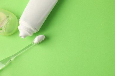 Photo of Toothbrush, toothpaste and floss on green background, flat lay. Space for text