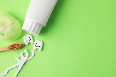 Photo of Different oral care products and teeth figures on green background, flat lay. Space for text