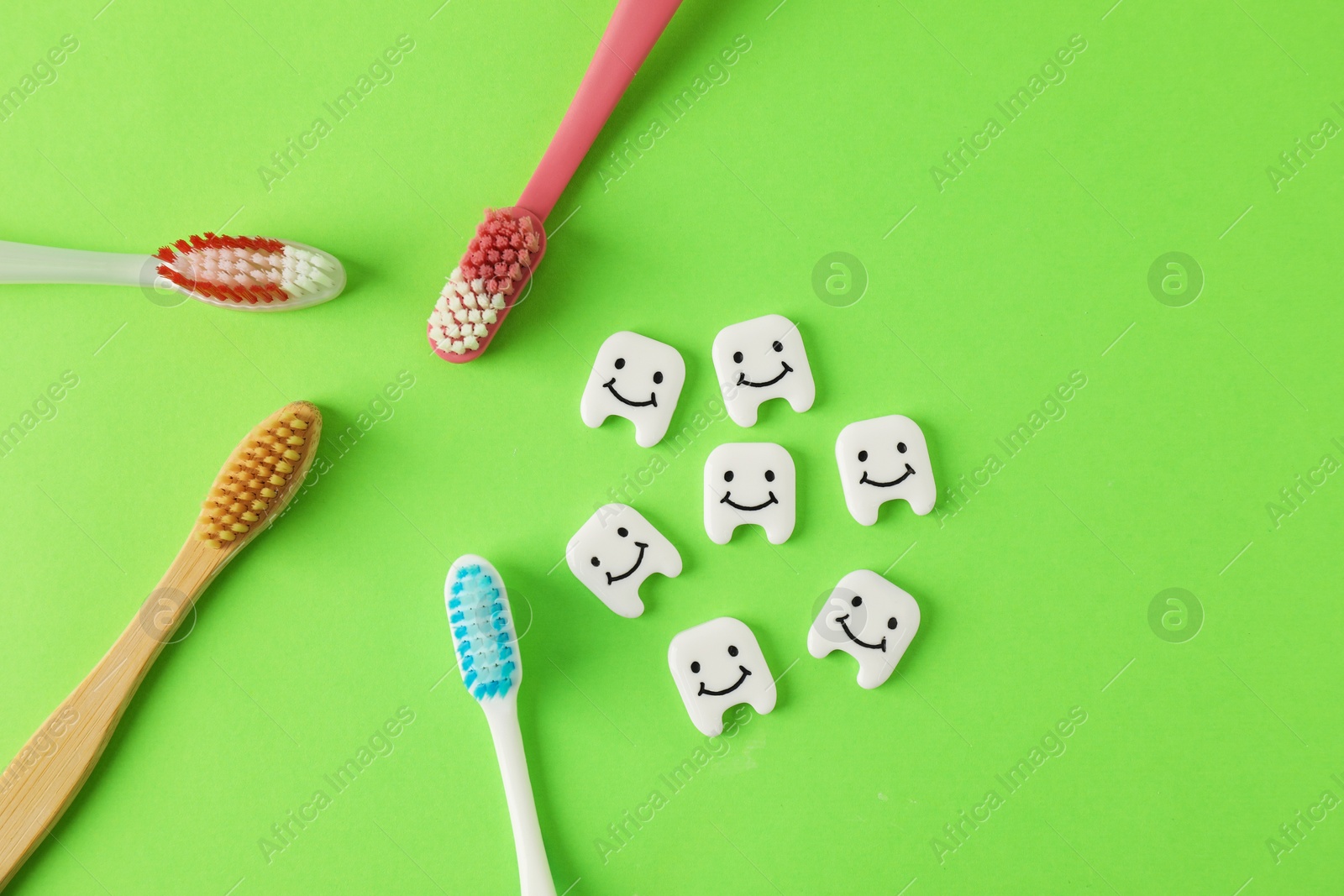 Different oral care products and teeth figures on green background, flat lay Photo of Different oral care products and teeth figures on green background, flat lay