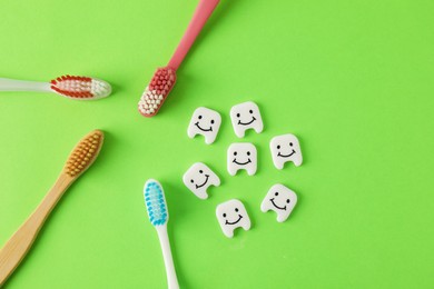 Photo of Different oral care products and teeth figures on green background, flat lay