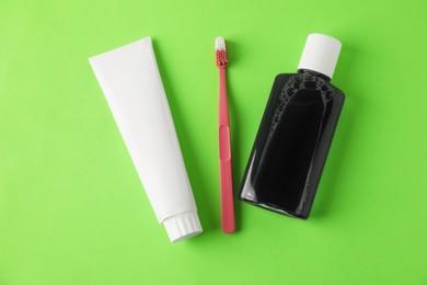 Photo of Toothbrush, toothpaste and mouthwash on green background, flat lay