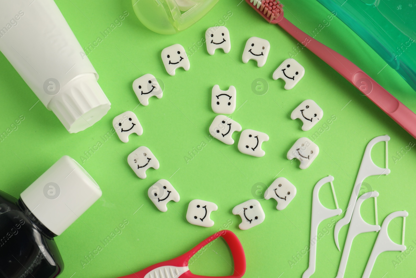 Different oral care products and teeth figures on green background, flat lay Photo of Different oral care products and teeth figures on green background, flat lay