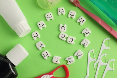 Photo of Different oral care products and teeth figures on green background, flat lay