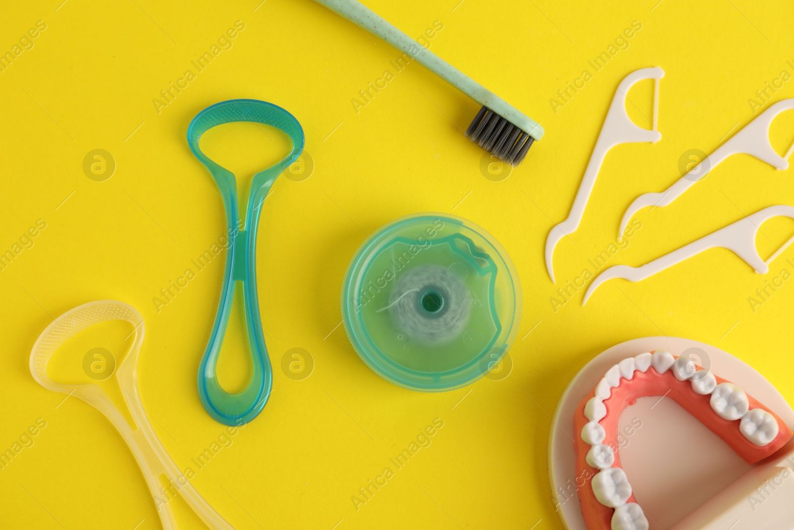 Different oral care products and dental model on yellow background, flat lay Photo of Different oral care products and dental model on yellow background, flat lay