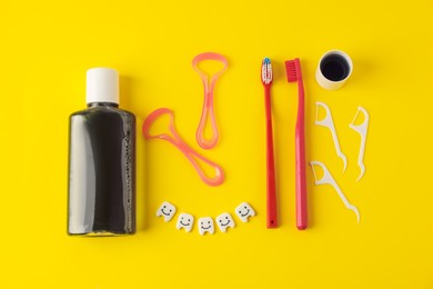 Photo of Different oral care products and teeth figures on yellow background, flat lay