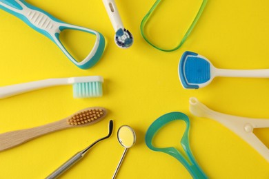 Photo of Different oral care products on yellow background, flat lay