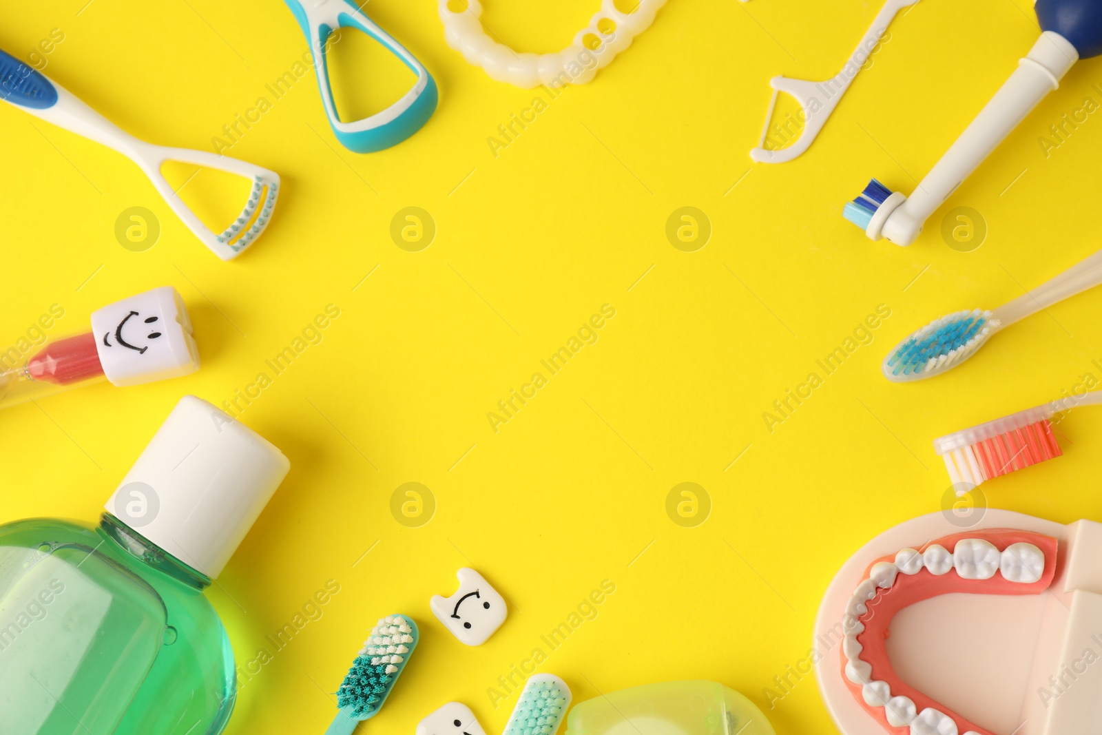 Photo of Frame of different oral care products and dental model on yellow background, flat lay. Space for text