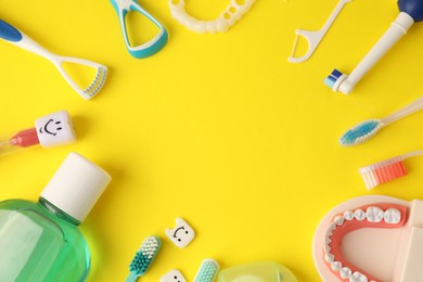 Photo of Frame of different oral care products and dental model on yellow background, flat lay. Space for text