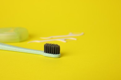 Photo of Toothbrush and floss picks on yellow background, closeup. Space for text