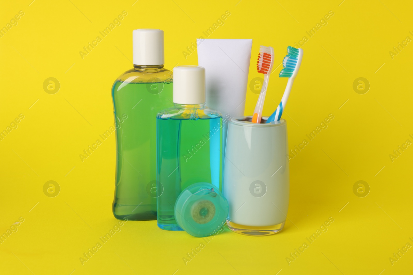 Photo of Different oral care products on yellow background