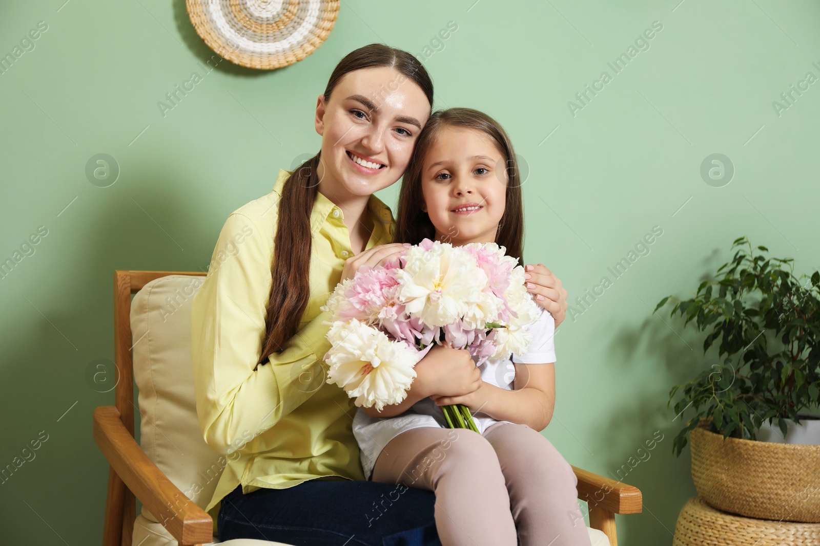 Mother and her daughter with bouquet of beautiful peonies at home Photo of Mother and her daughter with bouquet of beautiful peonies at home