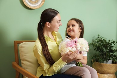 Photo of Mother and her daughter with bouquet of beautiful peonies at home
