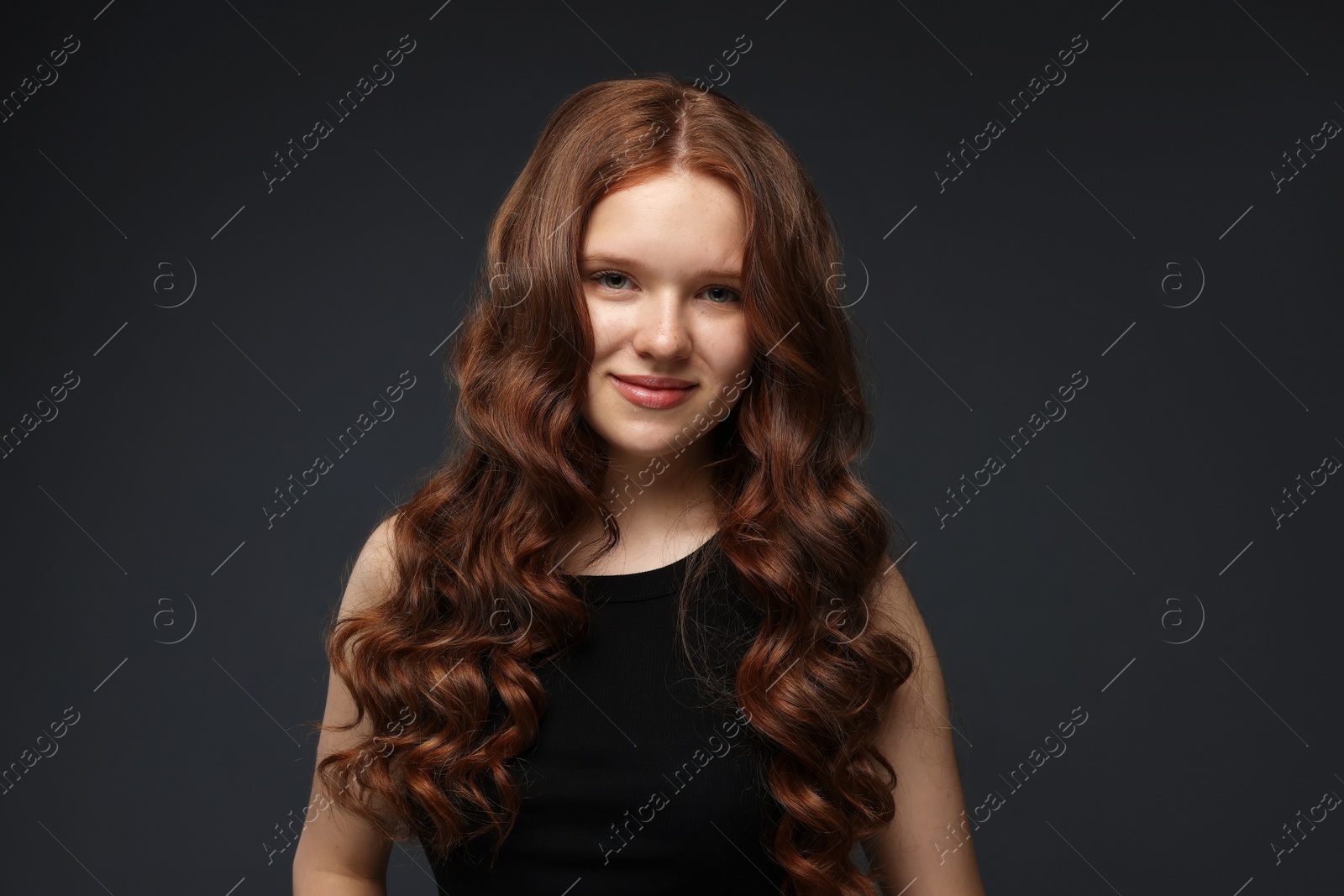 Portrait of beautiful teenage girl with healthy wavy hair on dark grey background Photo of Portrait of beautiful teenage girl with healthy wavy hair on dark grey background