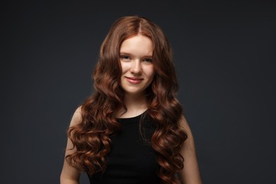 Photo of Portrait of beautiful teenage girl with healthy wavy hair on dark grey background