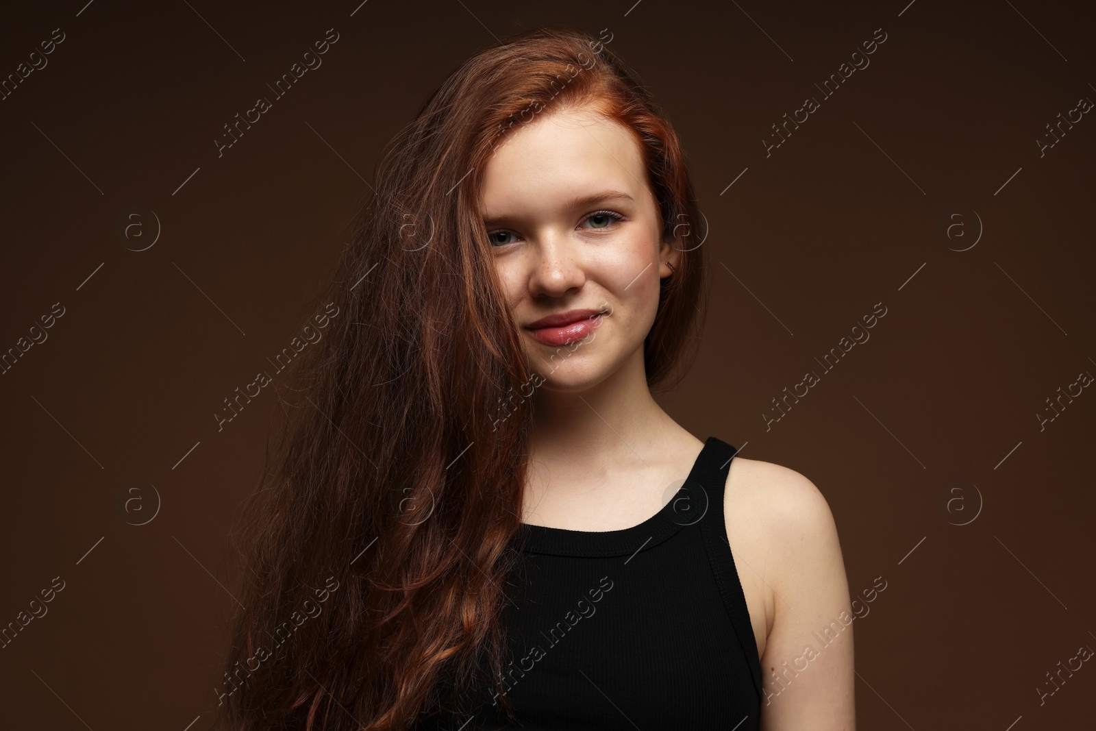 Photo of Portrait of beautiful teenage girl with healthy wavy hair on brown background