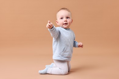 Photo of Cute little baby crawling on beige background