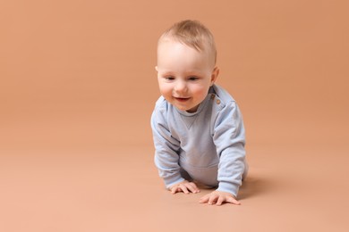 Photo of Cute little baby crawling on beige background, space for text
