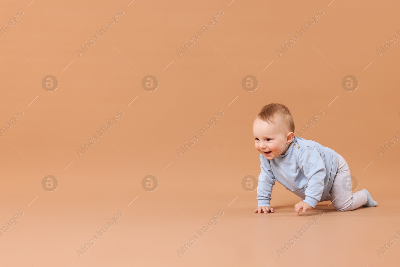 Cute little baby crawling on beige background, space for text Photo of Cute little baby crawling on beige background, space for text