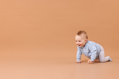 Photo of Cute little baby crawling on beige background, space for text