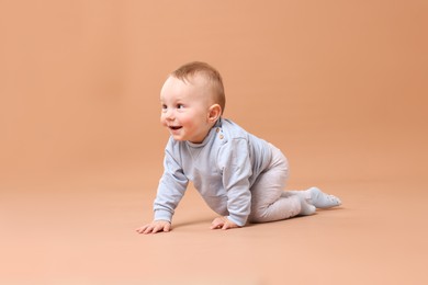 Photo of Cute little baby crawling on beige background
