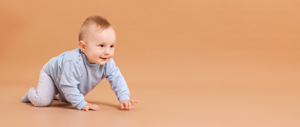 Photo of Cute little baby crawling on beige background, space for text