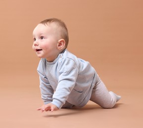 Photo of Cute little baby crawling on beige background