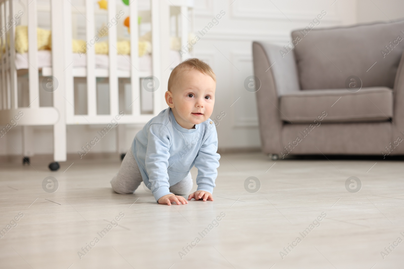 Cute little baby crawling on floor at home, space for text Photo of Cute little baby crawling on floor at home, space for text