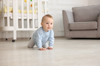 Photo of Cute little baby crawling on floor at home, space for text