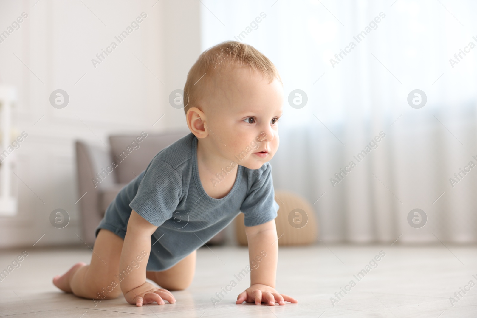 Cute little baby crawling on floor at home, space for text Photo of Cute little baby crawling on floor at home, space for text