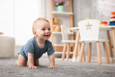 Photo of Cute little baby crawling on floor at home, space for text