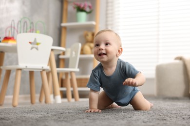 Photo of Cute little baby crawling on floor at home, space for text