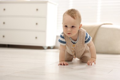 Photo of Cute little baby crawling on floor at home, space for text