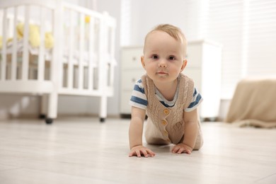 Photo of Cute little baby crawling on floor at home, space for text