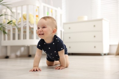 Photo of Cute little baby crawling on floor at home, space for text
