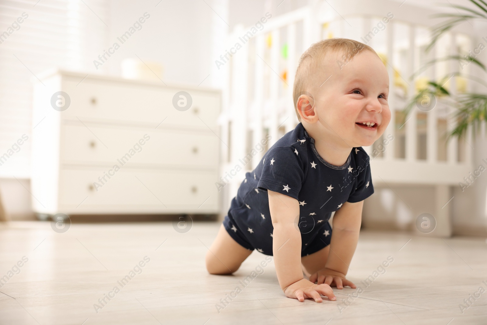 Cute little baby crawling on floor at home, space for text Photo of Cute little baby crawling on floor at home, space for text