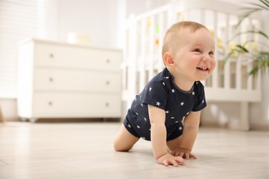 Photo of Cute little baby crawling on floor at home, space for text