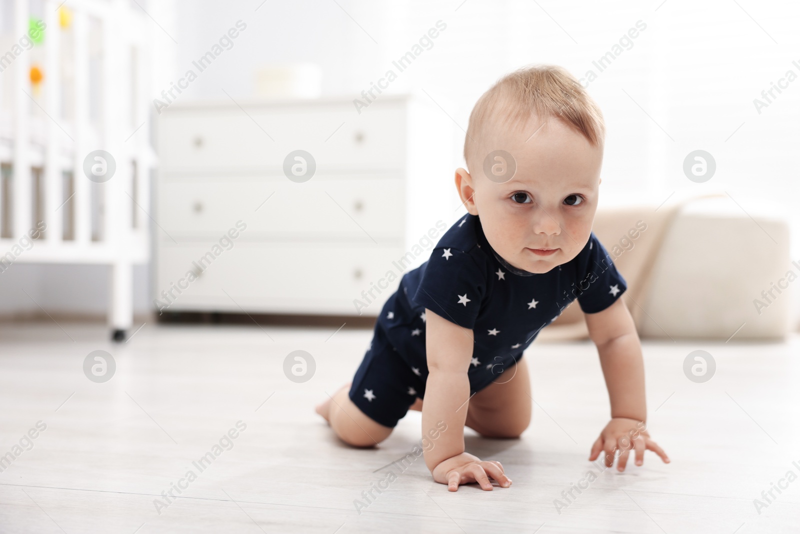 Cute little baby crawling on floor at home, space for text Photo of Cute little baby crawling on floor at home, space for text