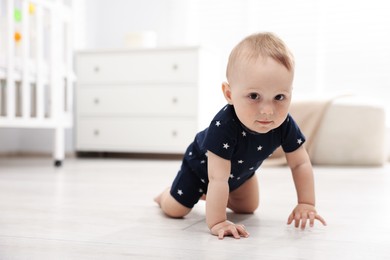 Photo of Cute little baby crawling on floor at home, space for text