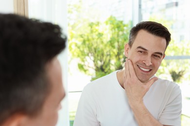 Photo of Smiling man after shaving near mirror at home