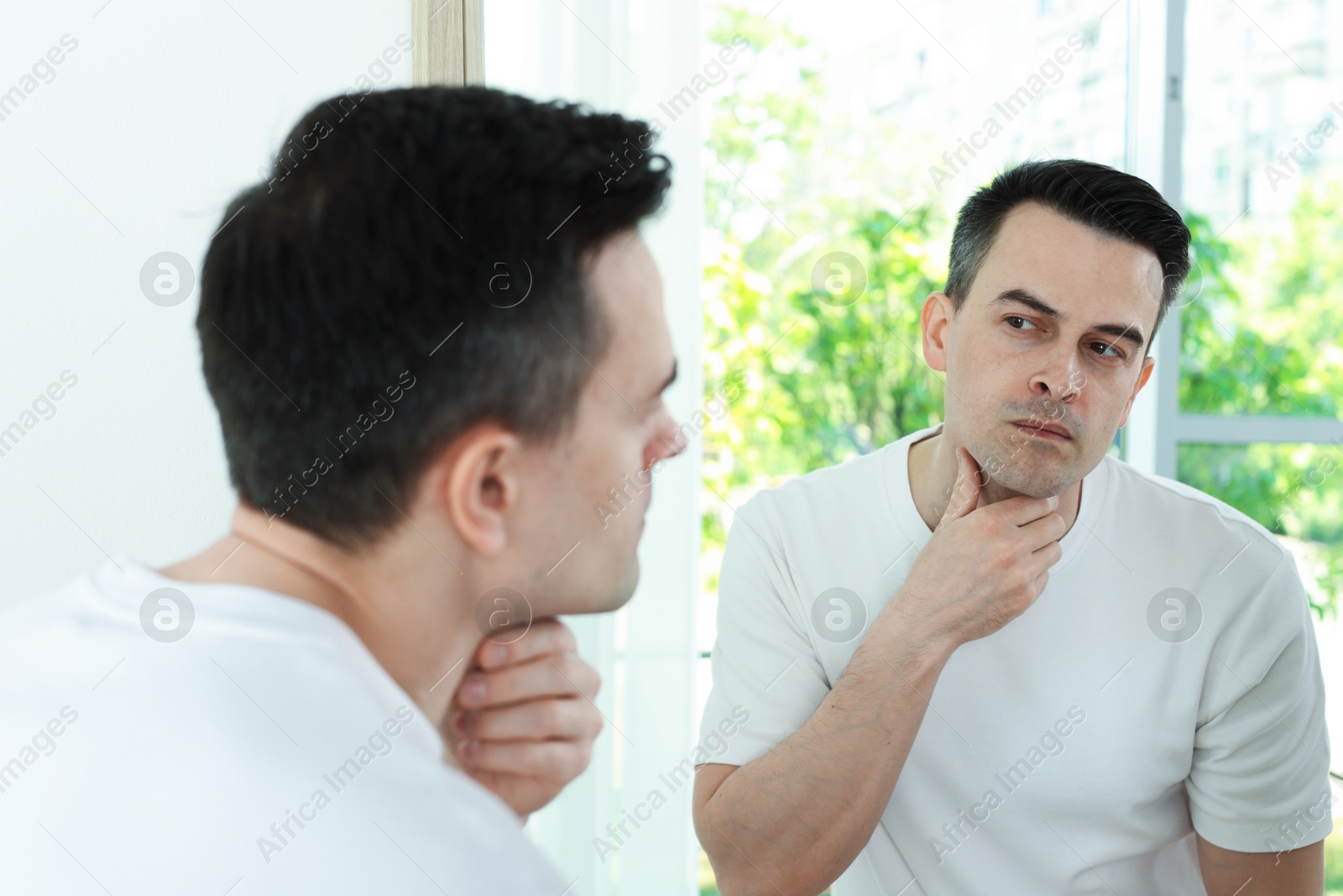 Handsome man after shaving near mirror at home Photo of Handsome man after shaving near mirror at home