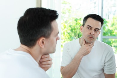 Photo of Handsome man after shaving near mirror at home