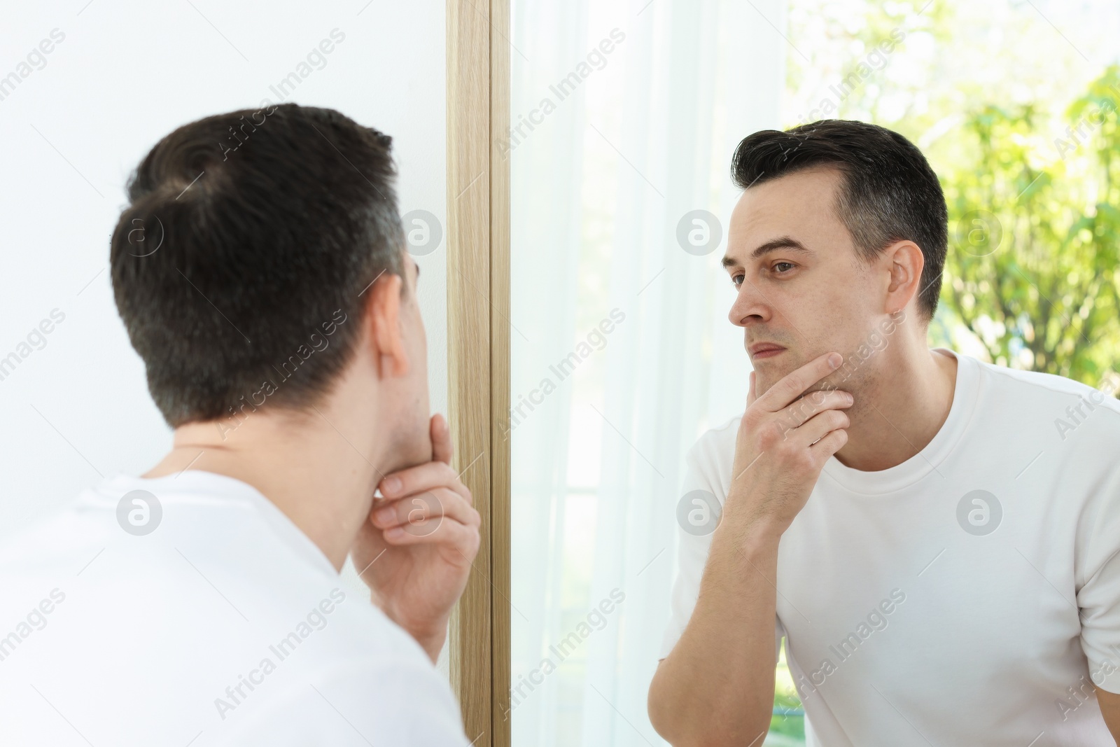 Handsome man after shaving near mirror at home Photo of Handsome man after shaving near mirror at home