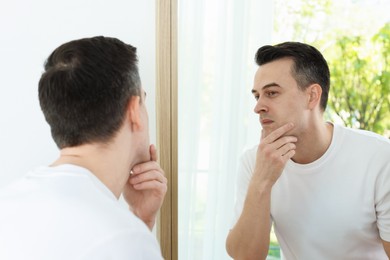 Photo of Handsome man after shaving near mirror at home