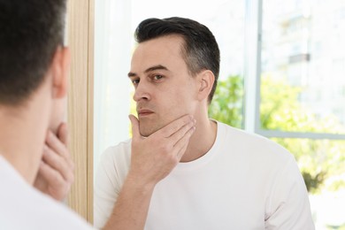 Photo of Handsome man after shaving near mirror at home