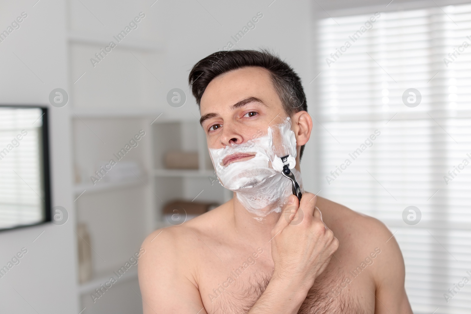 Handsome man shaving with razor at home Photo of Handsome man shaving with razor at home