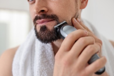 Photo of Man shaving with trimmer at home, closeup