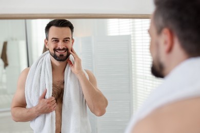 Photo of Smiling man before shaving looking at mirror in bathroom