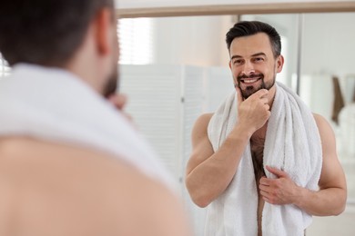 Photo of Smiling man before shaving looking at mirror in bathroom